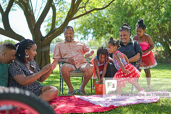 Mehrgenerationen-Familie beim Wasserspritzen im Sommerpark