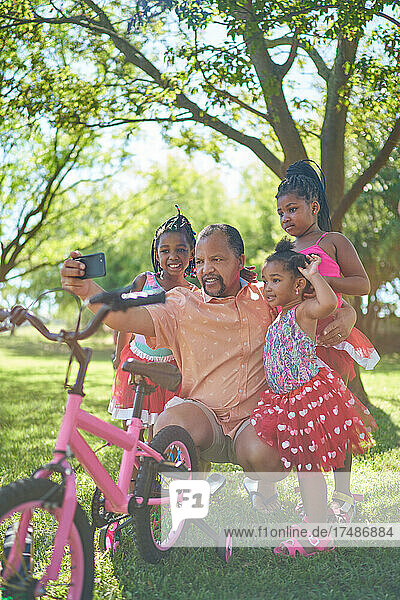 Großvater und Enkeltöchter machen ein Selfie im Sommerpark