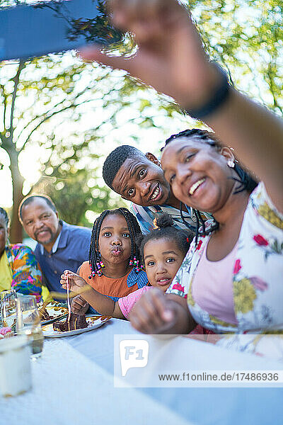 Mehrgenerationenfamilie macht Selfie am Terrassentisch