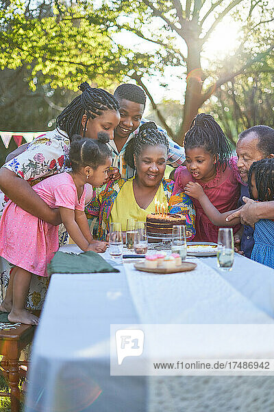 Mehrgenerationenfamilie feiert Geburtstag mit Kuchen am Terrassentisch