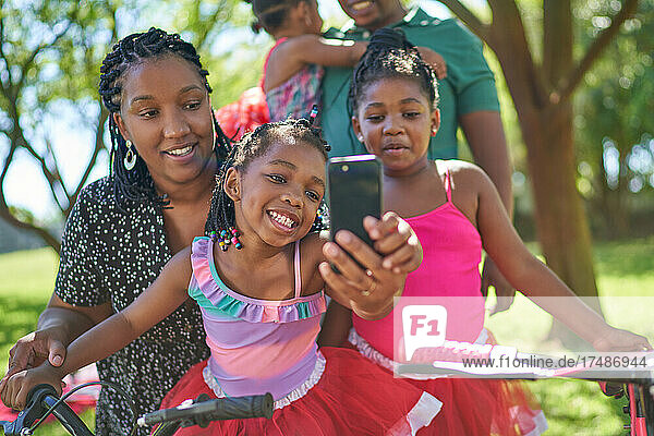 Happy mother and daughters taking selfie in park