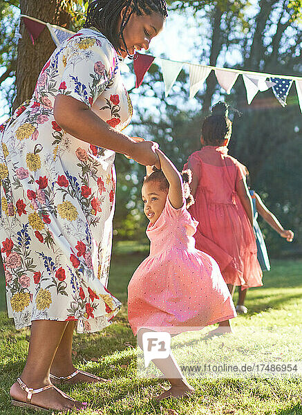 Glückliche Mutter und Tochter tanzen im sonnigen Sommer Hinterhof