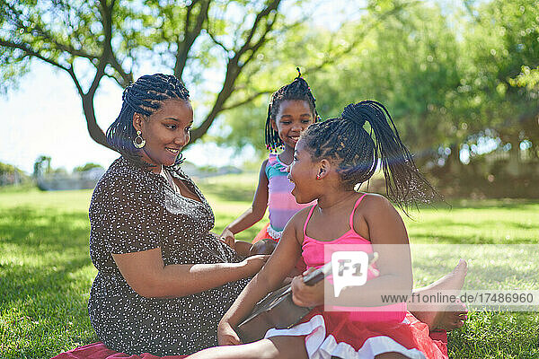 Mutter und Töchter spielen Ukulele im Sommerpark