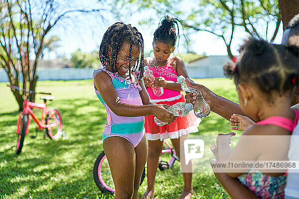 Verspielte Mädchen spritzen Wasser im Sommerpark