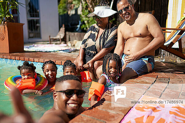 Porträt einer glücklichen Mehrgenerationenfamilie am sonnigen Sommerschwimmbad
