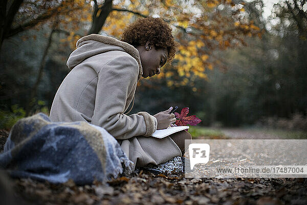 Young woman journaling in tranquil autumn park