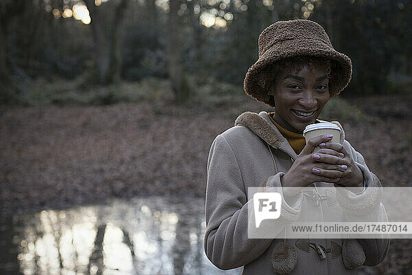 Porträt glückliche junge Frau trinkt Kaffee im Herbst Park
