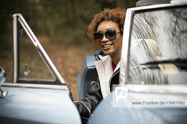 Portrait happy carefree young woman getting out of convertible
