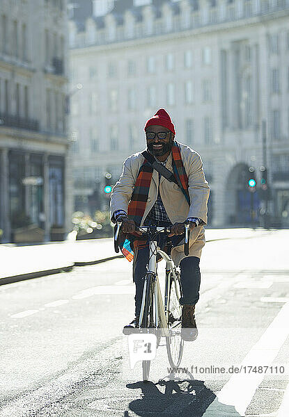 Happy man riding bicycle on sunny city street
