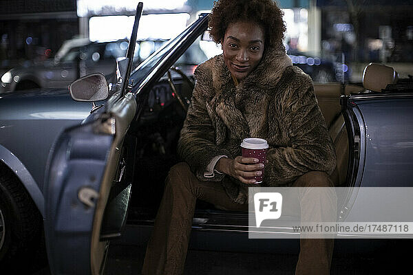 Porträt selbstbewusste junge Frau mit Kaffee im Cabrio