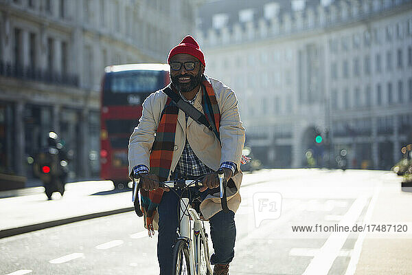 Happy businessman riding bicycle on sunny city street  London  UK
