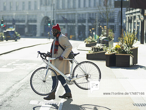 Businessman carrying bicycle on sunny city street