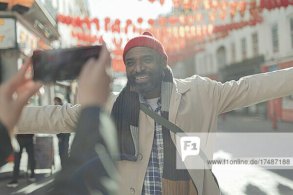 Frau fotografiert glücklichen Mann auf sonniger Stadtstraße
