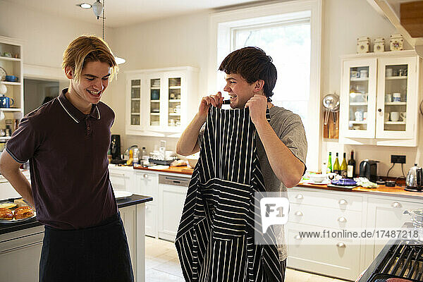 Glückliche Teenager mit Schürze beim Kochen in der Küche