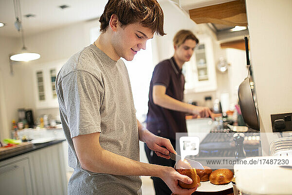 Jugendlicher schneidet Hamburgerbrötchen in der Küche