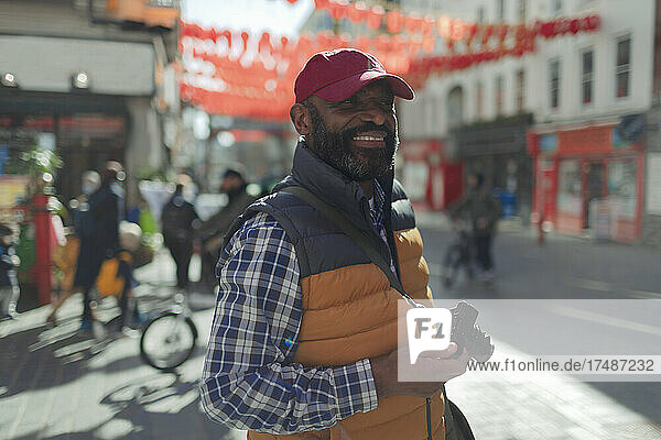 Happy male tourist with digital camera on city street