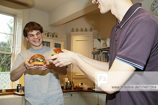 Glückliche Teenager essen Hamburger zu Hause