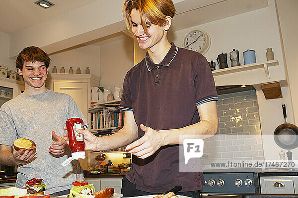 Teenage boys preparing hamburgers in kitchen