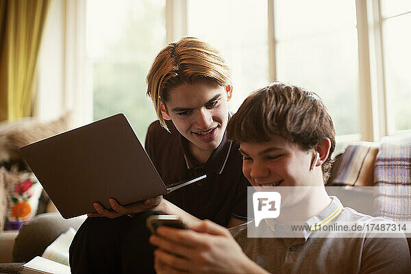 Teenager-Jungen benutzen Laptop und Smartphone im Wohnzimmer