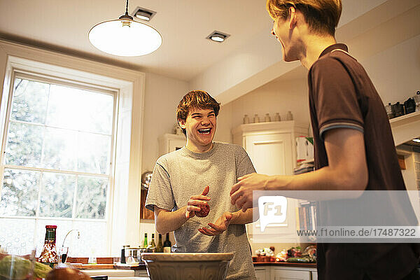 Happy teenage boys making hamburger patties in kitchen