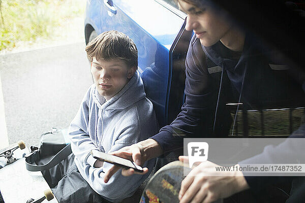 Teenage boys using smart phone at car