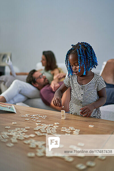 Süßes Kleinkind Mädchen Stapeln Scrabble Fliesen auf Couchtisch