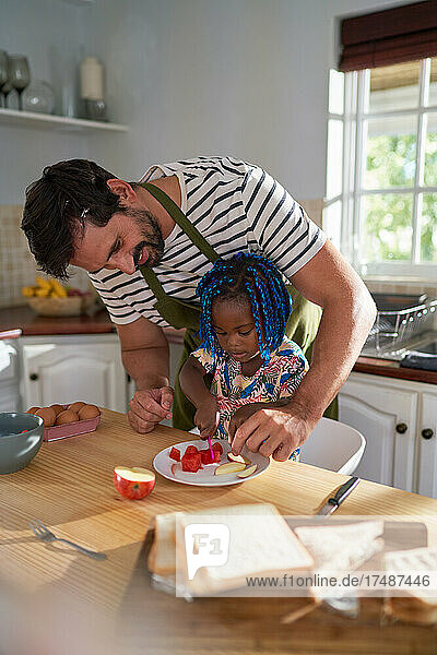 Vater hilft Tochter beim Obstschneiden in der Küche