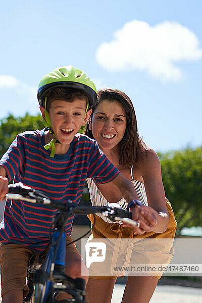 Glückliche Mutter hilft ihrem Sohn beim Fahrradfahren
