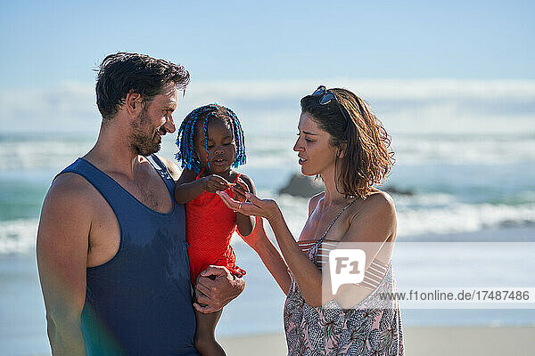 Parents with toddler daughter on sunny summer beach