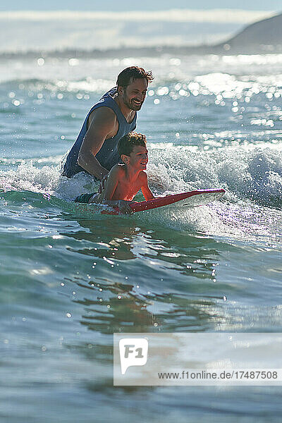 Glücklicher Vater und Sohn beim Bodyboarden im sonnigen Meer