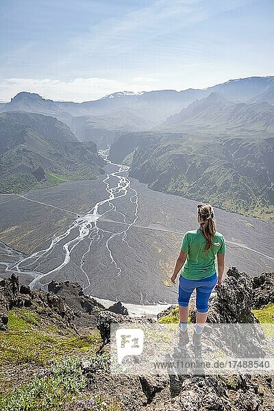 Wanderin blickt über Landschaft  Berge und Gletscherfluss in einem Bergtal  wilde Natur  hinten Gletscher Mýrdalsjökull  Isländisches Hochland  Þórsmörk  Suðurland  Island  Europa