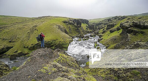 Hiker at a waterfall  landscape at Fimmvörðuháls hiking trail  South Iceland  Iceland  Europe