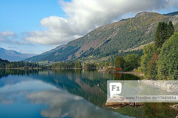 Häuser und Berge spiegeln sich in einem ruhigen See  Gaulartal. Norwegen