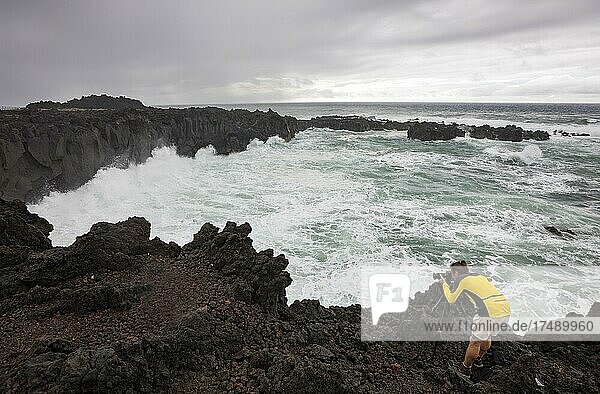 Fotograf an der vulkanischen Steilküste bei Flut mit hohen Wellen  Ponta da Ferraria  Insel Sao Miguel  Azoren  Portugal  Europa