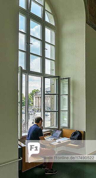 Ein Student sitzt zum Lernen mit seinem Laptop am Fenster in dem Gebäude der Humboldt Universität  Berlin  Deutschland  Europa