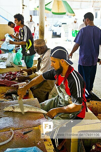 Männer entschuppen gegen Bares die Fische und verarbeiten sie mit großen Hackbeilen zu praktischen Einheiten  Fischmarkt Mutrah  Maskat  Muscat  Oman  Asien