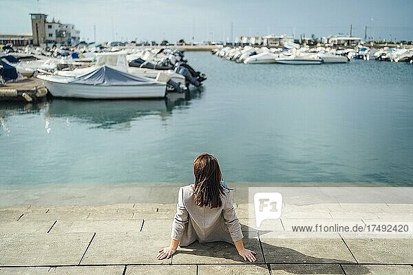 Junge Frau sitzt am Yachthafen in Faro  Algarve  Portugal  Europa