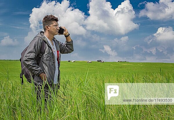 Man calling by cell phone  young man in the field calling by cell phone  young backpacker with cell phone in the field and copy space