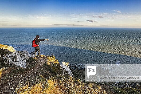 Wanderer auf Steilküste  zeigt auf das Meer  Beachy Head  Eastbourne  Sussex  England  Großbritannien  Europa