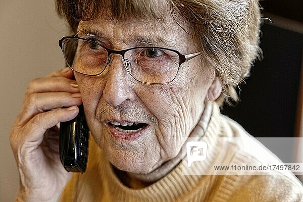 Seniorin zuhause beim Telefonieren mit einem Telefon in der Hand  Köln  Nordrhein-Westfalen  Deutschland  Europa