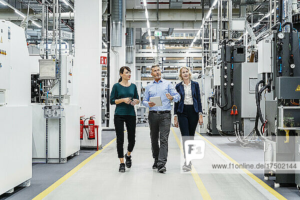 Businessman inspecting machinery with coworkers in electrical industry