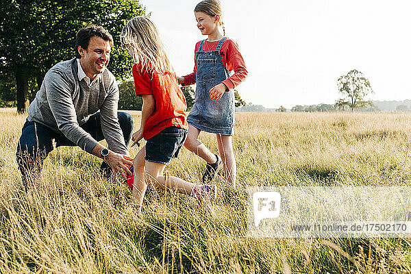Cheerful father playing with daughters in public park