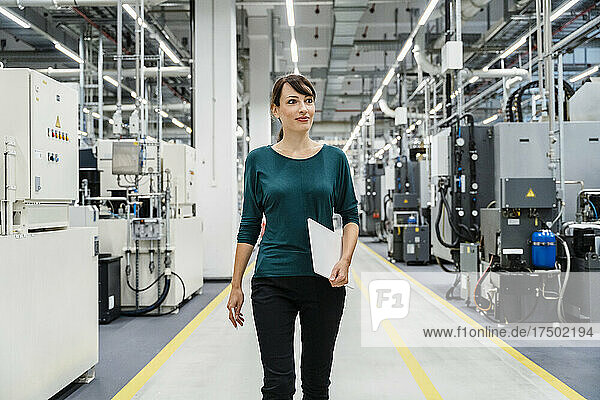 Smiling businesswoman with tablet PC in automated factory