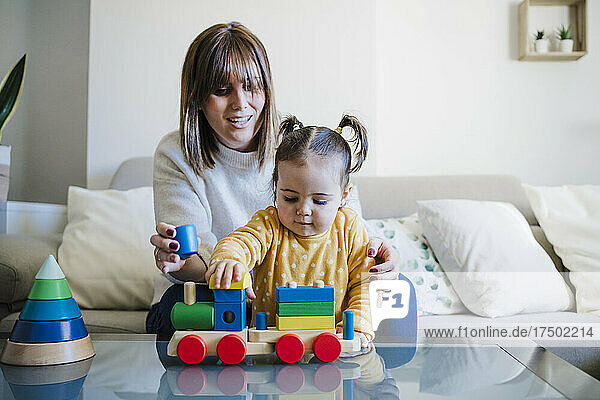 Mother and daughter playing with toy on table in living room