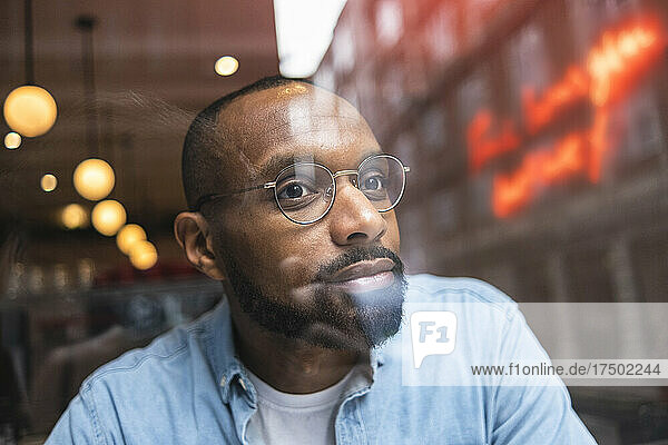 Man with eyeglasses day dreaming in cafe