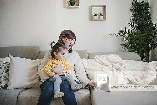 Woman using tablet PC with baby girl at home