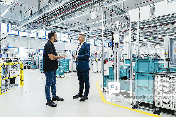 Maintenance engineer discussing with businessman in modern factory