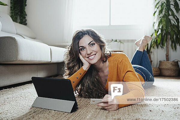 Frau hält zu Hause Kreditkarte per Tablet-PC in der Hand