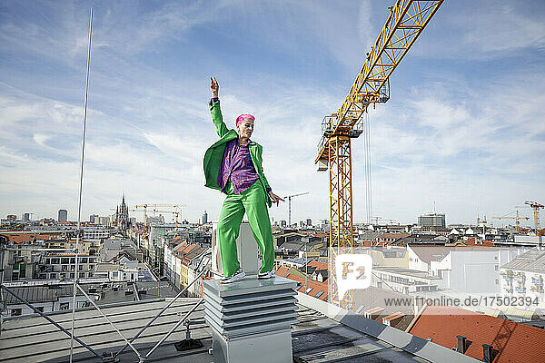 Carefree businesswoman with hand raised on rooftop