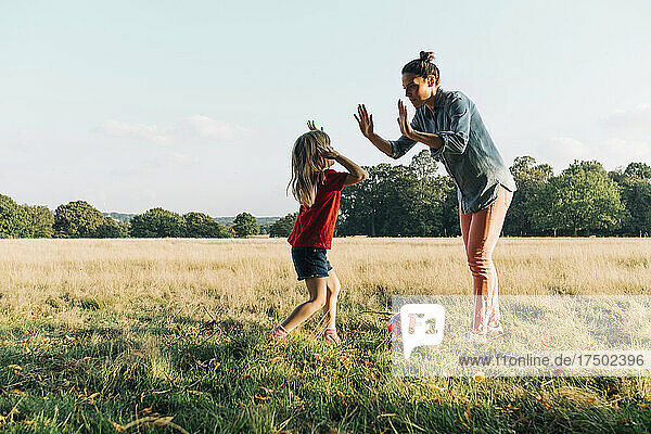 Mother giving high-five to daughter in park on weekend